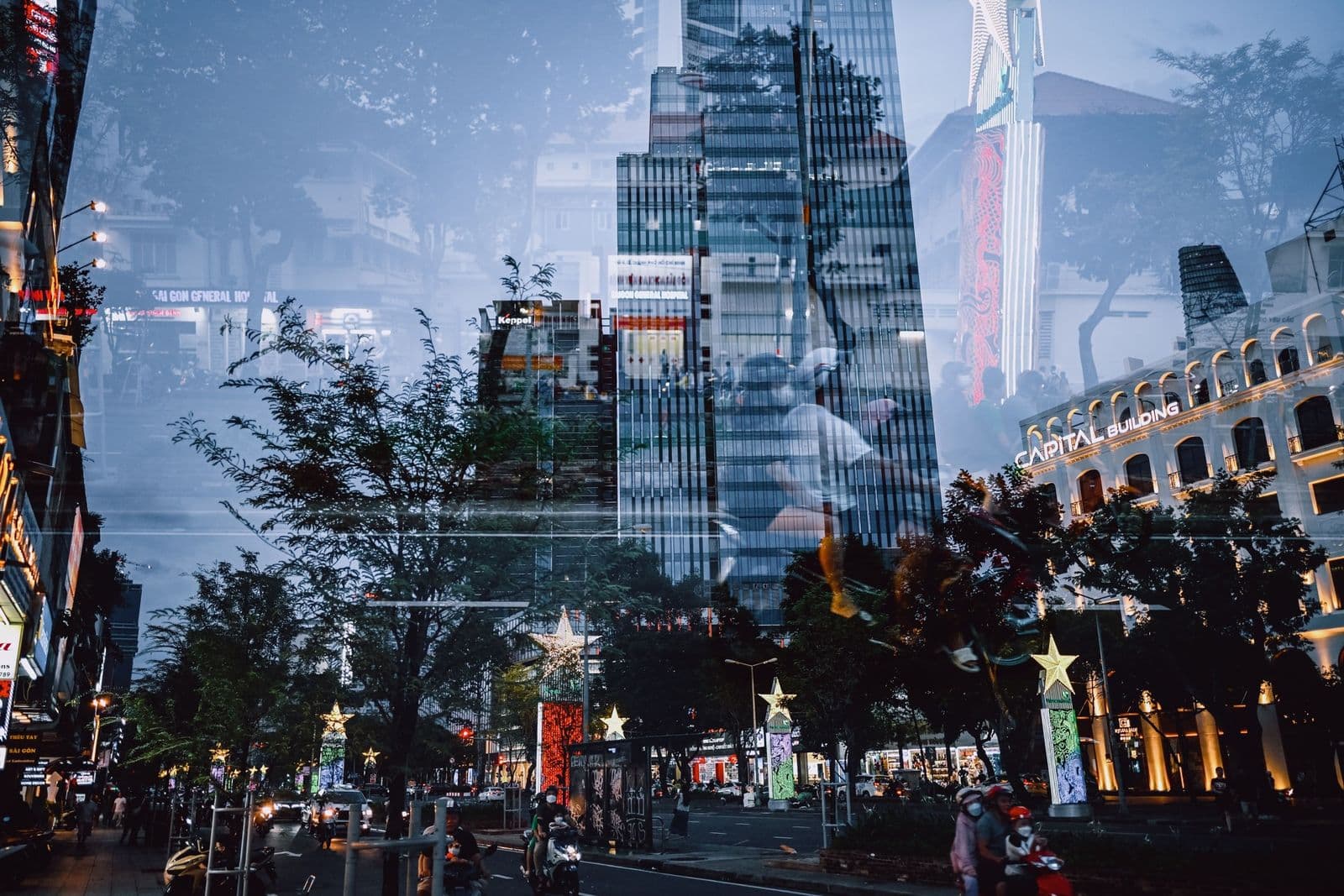 Double exposure of glass skyscrapers layered over a tree lined city street with traffic and street decorations